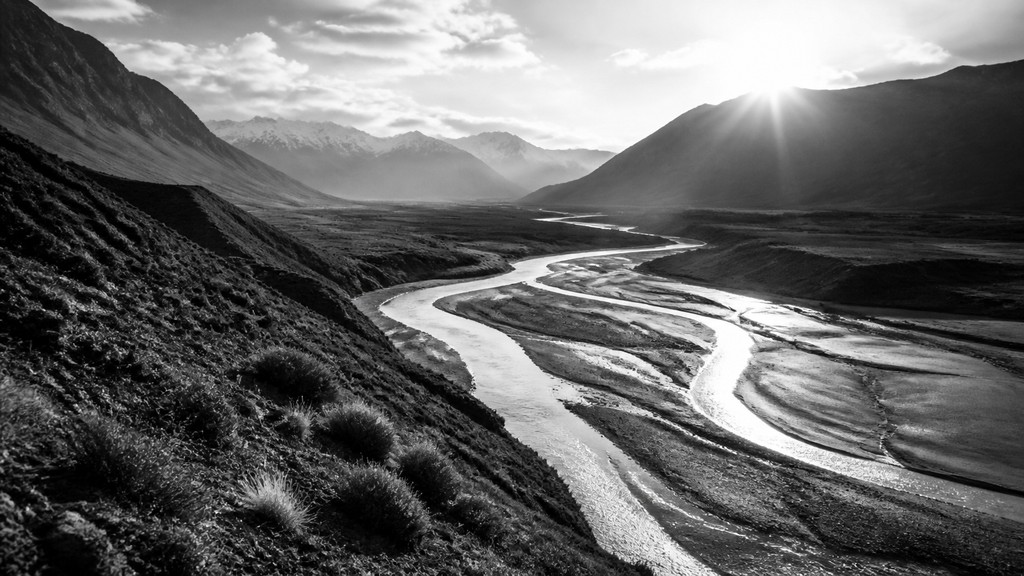 a vast valley with a river winding toward distant mountains at sunrise, no people, no text — Street Photography Style desktop wallpaper