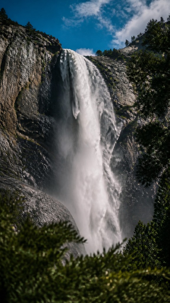 towering waterfall cascading down a cliff — Photographic Realism Art Style