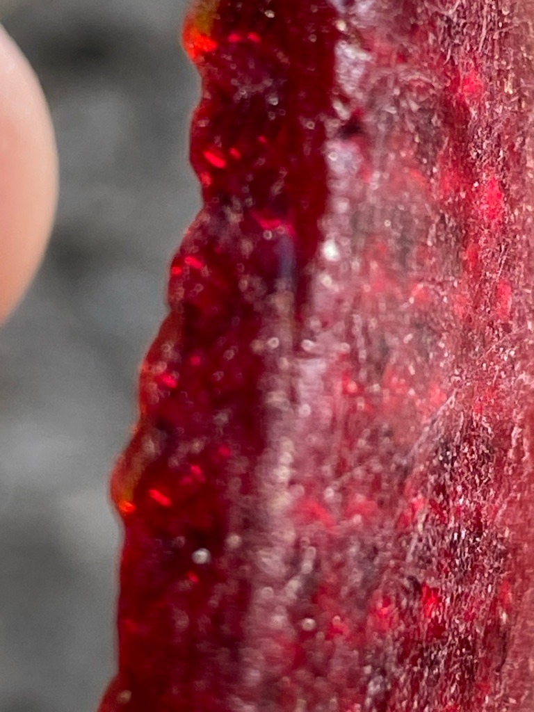 Not a diamond; appears to be a raw or translucent mineral slice, possibly red agate, carnelian, or treated quartz. - Irregular slab / uncut rough slice