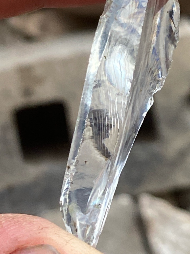 Not a diamond; this specimen appears to be optical or architectural glass, or potentially quartz/silica crystal with conchoidal fractures, displaying characteristic internal flow lines and melt features rather than diamond crystal faces or cleavage. - Irregular raw shard or fragment (uncut and unpolished, showing conchoidal fracture patterns).
