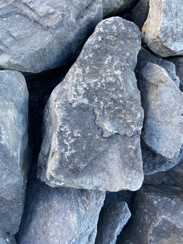 Not a diamond; these are naturally occurring silicate and mineral rock boulders, likely granite, basalt, or limestone used in landscaping or construction. - Irregular, unpolished natural rock formation.