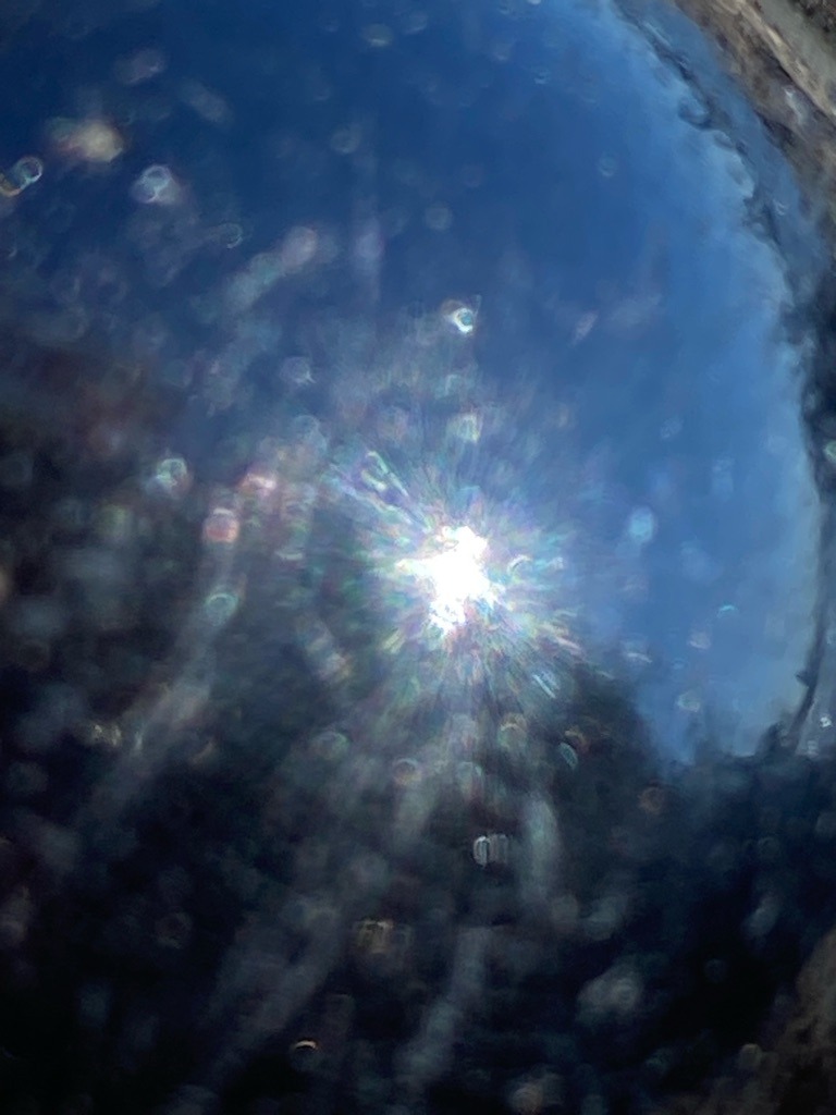 Unable to determine precisely from the image, appears to be an optical reflection or glare effect rather than a mounted or loose diamond specimen. - Not applicable; image shows an abstract light flare against a dark background.