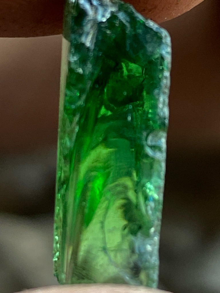 Not a diamond; this specimen appears to be green glass or synthetic emerald material due to visible internal gas bubbles and irregular fracture lines. - Rough elongated prismatic crystal/bar shape
