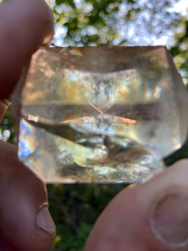The specimen shown in the image is not a diamond; based on the optical distortion, inclusions, refractive behavior, and raw crystal form visible, this appears to be a natural quartz crystal (potentially quartz var. citrine or a heavily included rock crystal quartz) or potentially glass/synthetic simulants, rather than a genuine diamond. - Rough or irregularly faceted crystal form, partially tumbled or crudely shaped, roughly rectangular or blocky tabular geometry.