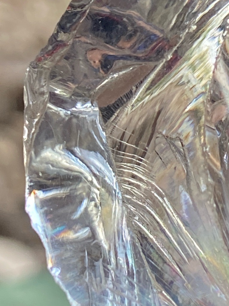 Not a diamond; visual characteristics strongly suggest quartz, glass, or obsidian exhibiting conchoidal fracture and iridescent surface films. - Irregular / Raw Crystalline Fragment
