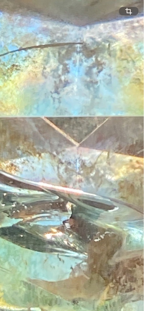 Unable to determine conclusively from the provided macro/distorted image, potentially natural or synthetic mineral given the surface reflections and inclusions. - Not clearly determinable due to extreme close-up of internal facets and reflections.