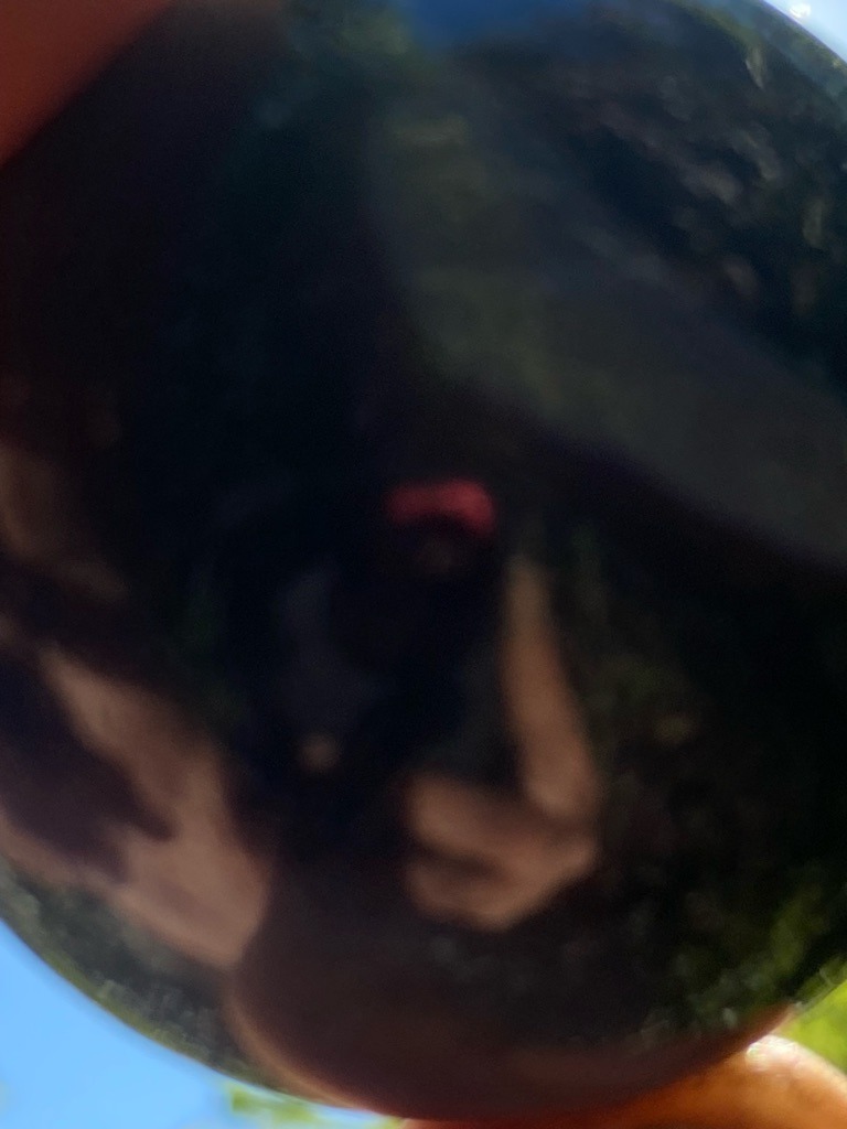 Unable to determine accurately from the provided image due to blur and heavy reflection - Round (appears spherical or polished sphere, not a standard faceted brilliant cut)