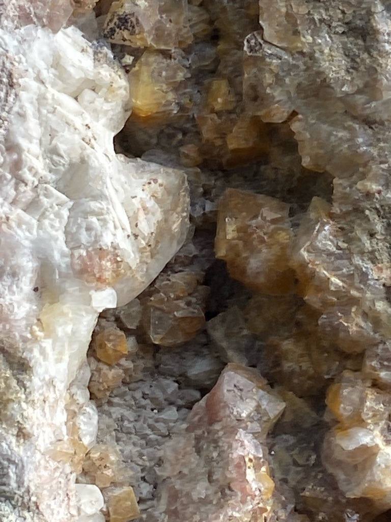 The image shows a raw mineral matrix containing crystalline structures, but does not display a cut or polished diamond. - Not applicable as this is a rough mineral cluster in matrix, not a faceted gemstone.