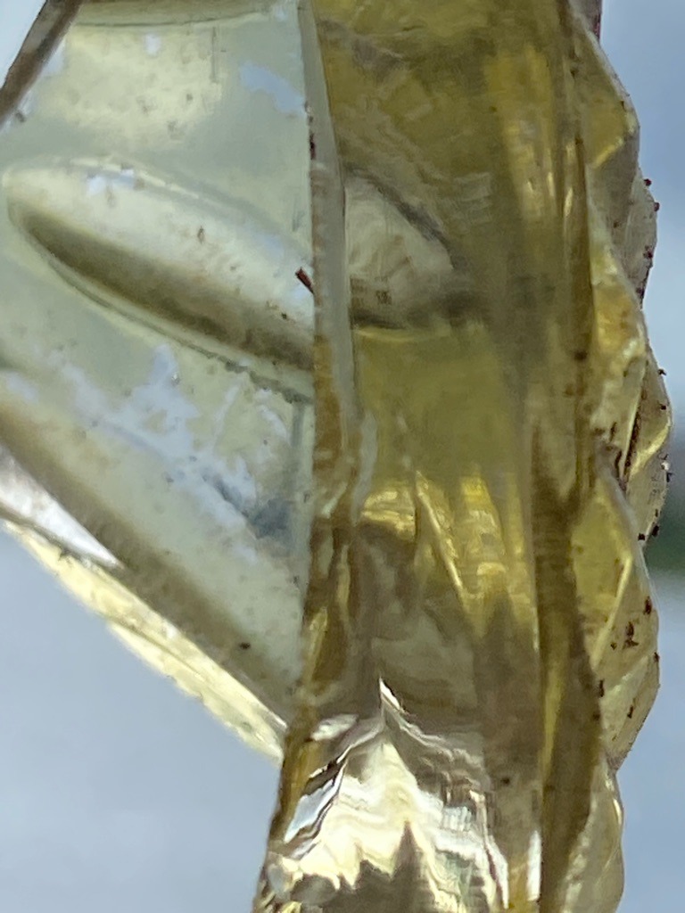 The image shows a carved or faceted piece of yellow-hued material, but visually it exhibits characteristics more consistent with synthetic glass, resin, or quartz rather than a genuine diamond. Further gemological testing such as thermal conductivity would confirm. - Irregular carved or faceted artistic shape, not a standard diamond cut.