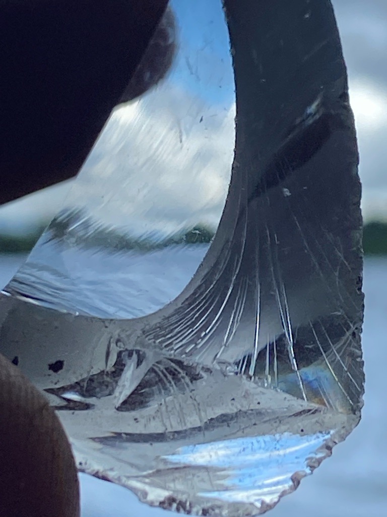 Not a diamond; this specimen is a piece of glass exhibiting characteristic conchoidal fracture patterns. - Irregular fragment with curved conchoidal breakage