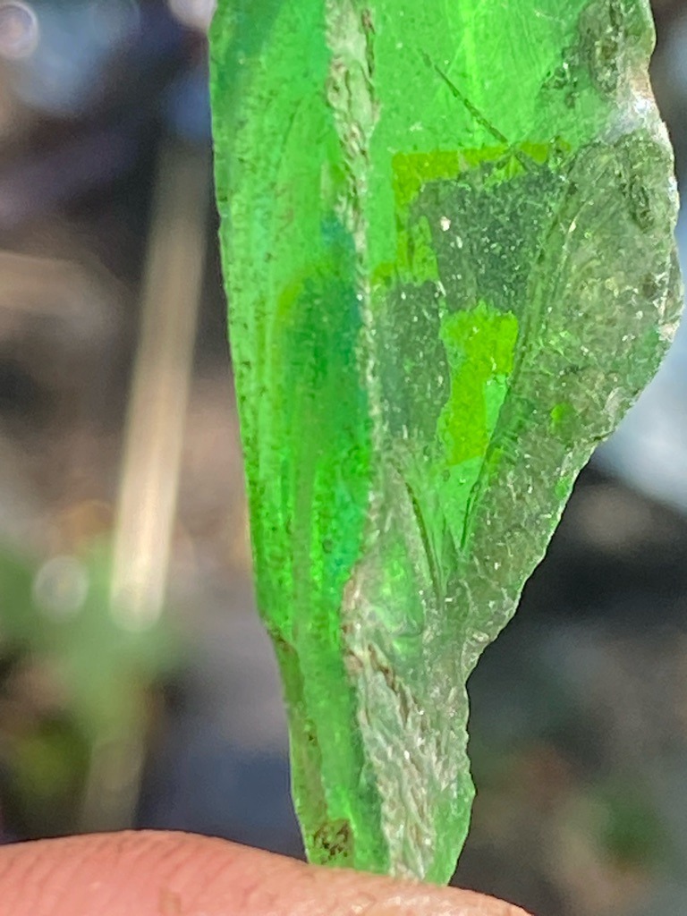 Not a diamond; this is a piece of green sea glass or weathered glass. - Irregular, raw, unstructured shard fragment.