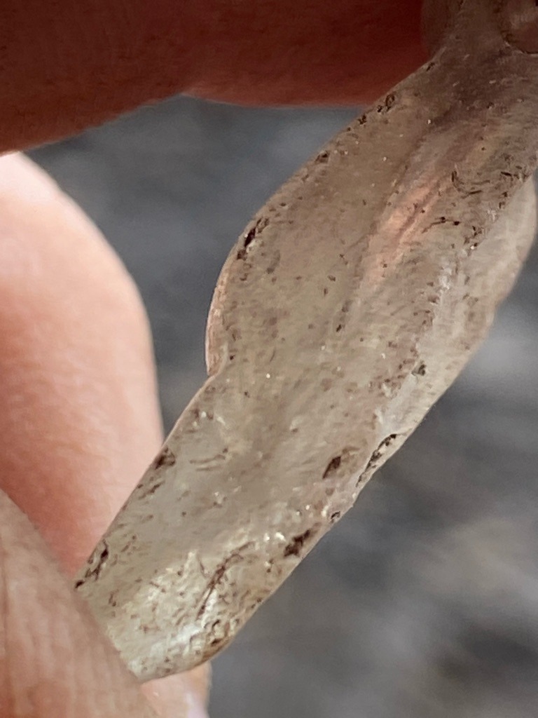 The provided image displays a rough, unprocessed natural diamond crystal, heavily included and contaminated with surface impurities. - Irregular / Rough Crystal (Macle or distorted octahedral form)