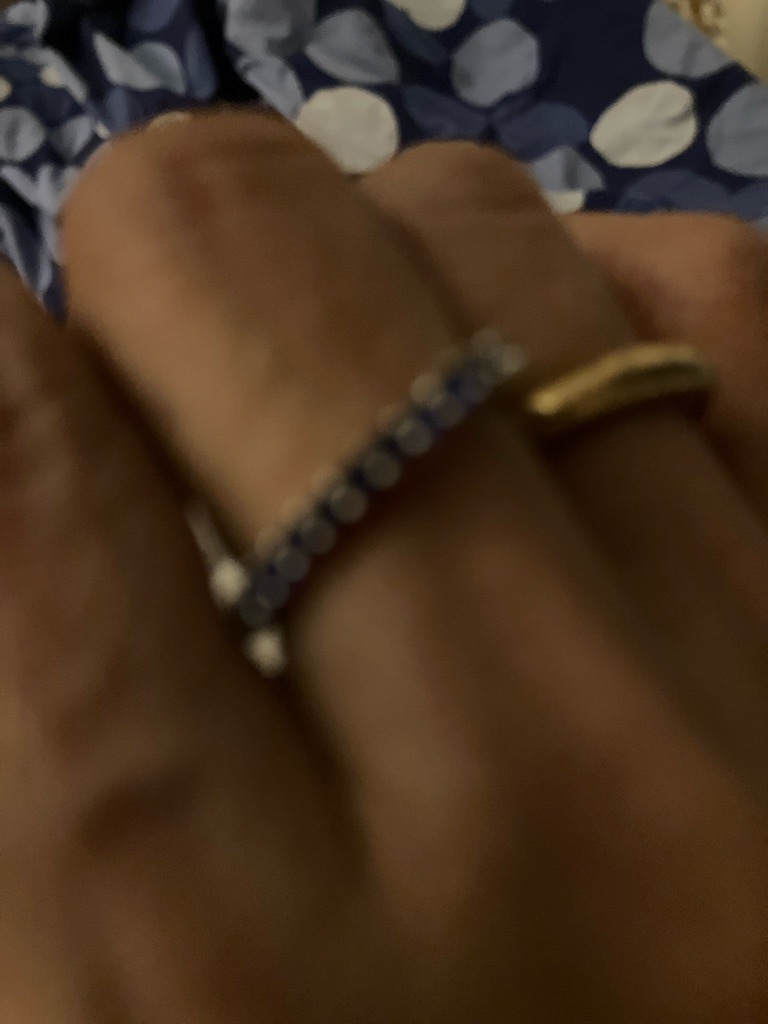 Unable to definitively confirm due to image blur; appears to be an alternating diamond and sapphire or blue gemstone band. Based on typical jewelry of this style, diamonds are likely natural melee. - Round Brilliant
