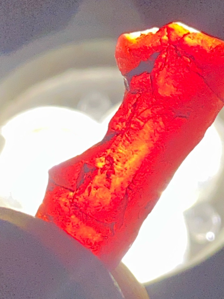 Not a diamond; this appears to be a natural mineral specimen, possibly red coral or jasper under intense backlight. - Rough irregular specimen