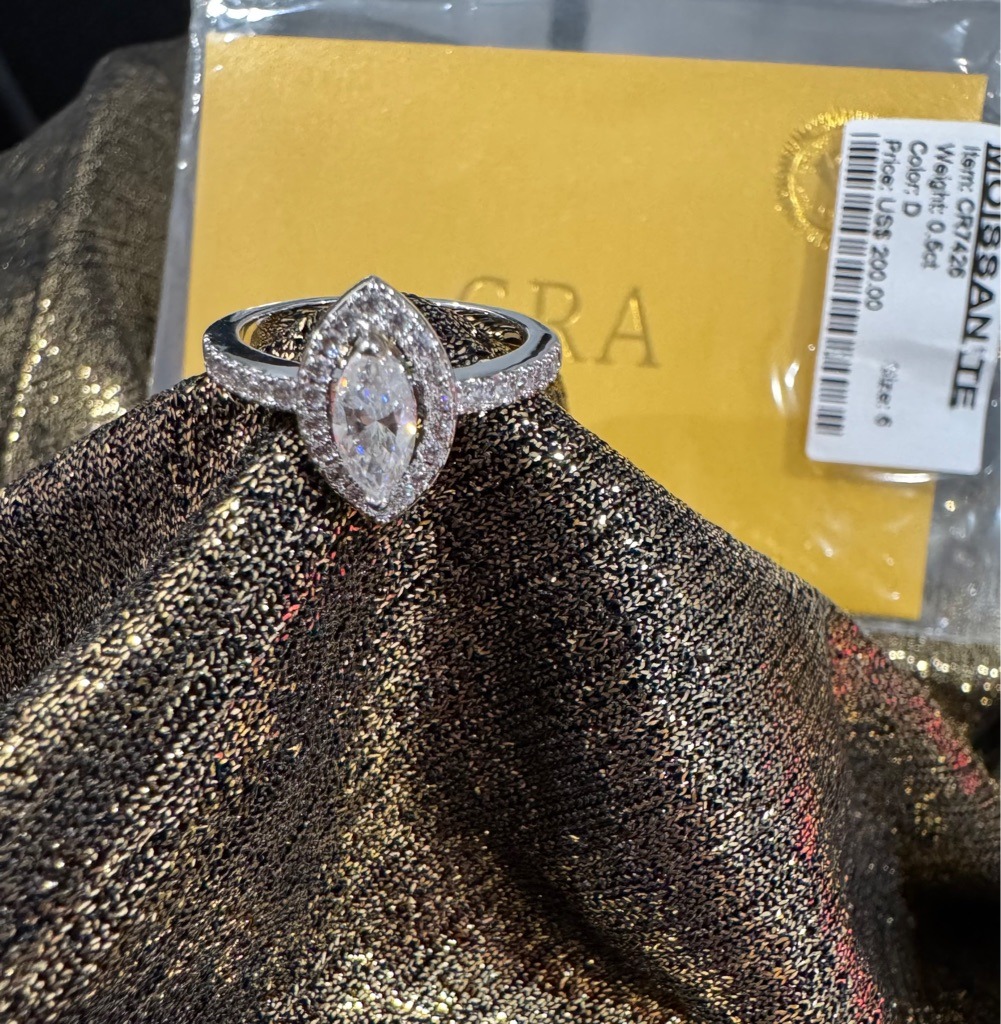 Moissanite (indicated by the label in the background showing MOISSANITE) - Marquise