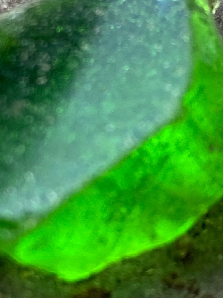 Not a diamond; visual indicators reveal this to be green glass / slag or potentially synthetic green quartz/yttrium aluminum garnet due to internal spherical gas bubbles visible under magnification. - Irregular raw nodule / tumbled fragment with a polished window facet