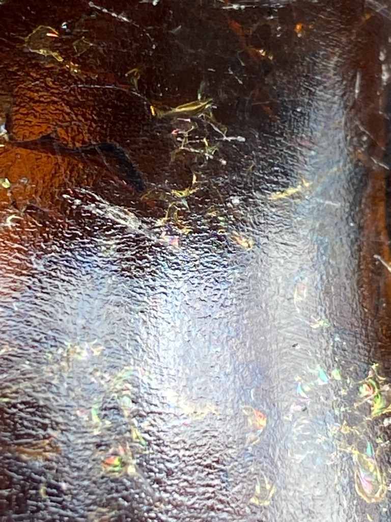 Not Applicable - The image does not show a diamond, but rather a textured, reflective brown surface with iridescent inclusions or crystalline flakes (possibly amber, resin, or a treated organic/synthetic composite material). - Not Applicable