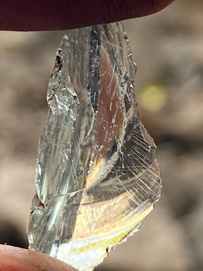 Not a diamond (appears to be quartz, glass, or a synthetic silicate crystal with striations and conchoidal fracture patterns) - Rough crystal / Irregular fragment