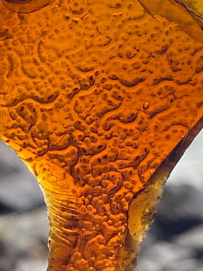 Not a diamond. The image displays a close-up texture resembling amber, resin, or molten glass rather than a crystalline diamond structure. - N/A - Irregular fragment or molten form