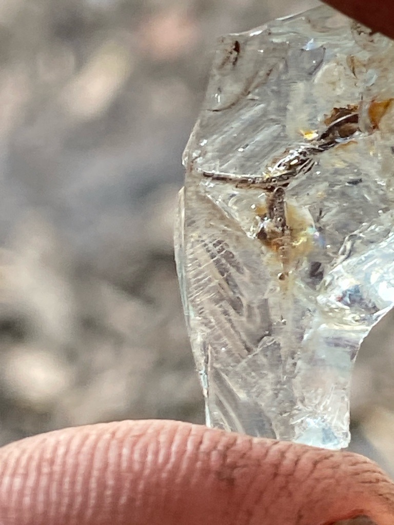 Not a diamond; this specimen appears to be raw quartz crystal or optical glass with significant internal fractures and trapped mineral inclusions. - Raw, unpolished crystal fragment with irregular fracture surfaces.