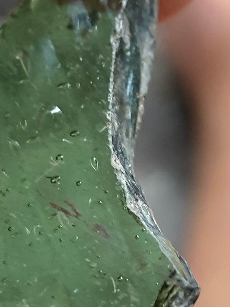 Not a diamond; this material exhibits characteristic rounded gas bubbles indicative of manufactured green glass or slag. - Raw, unpolished fragment / Irregular shard