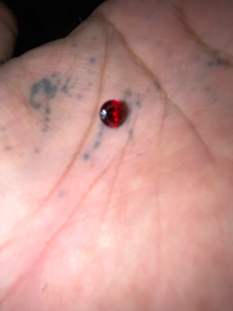 Not a diamond; visually appears to be a red gemstone such as a ruby, garnet, or colored glass/synthetic simulant - Round Brilliant