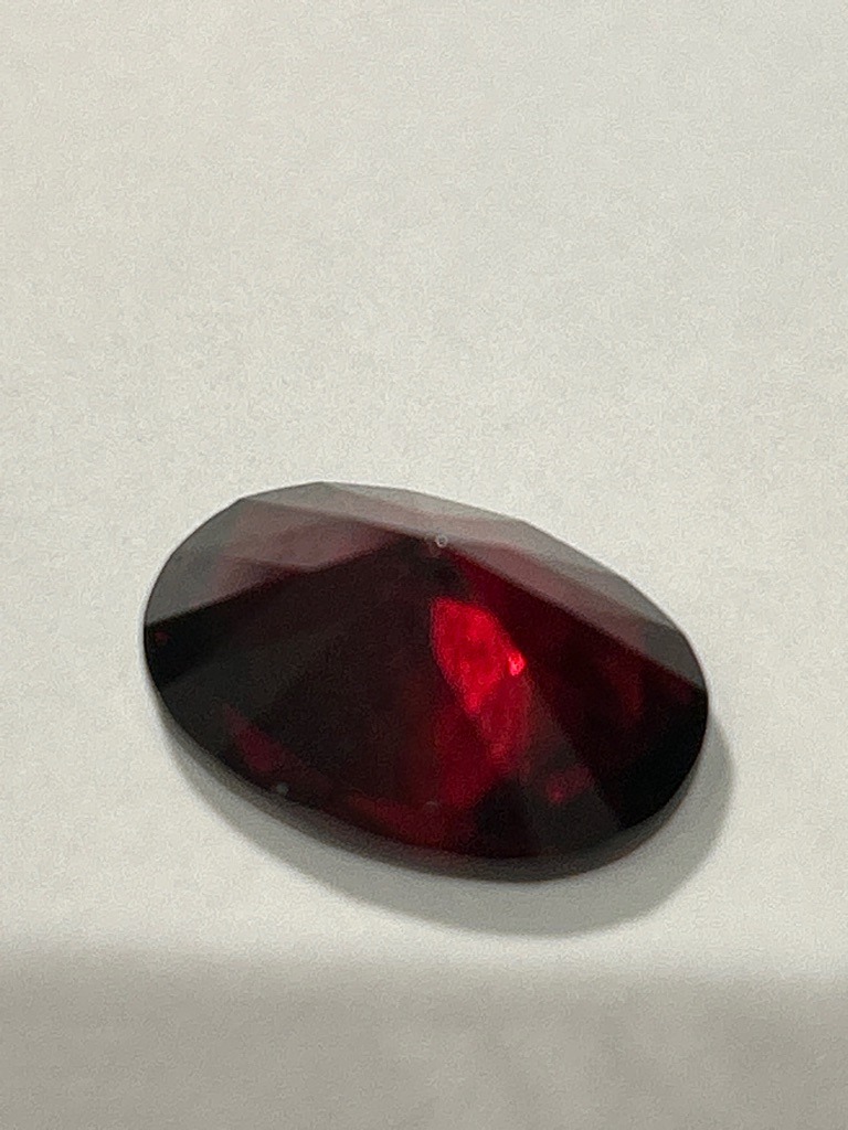 Natural colored diamond (or likely colored gemstone/ruby/garnet based on visual appearance) - Oval