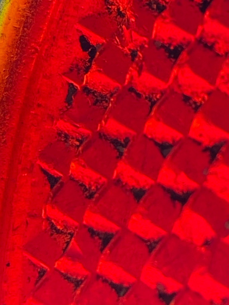 Not a diamond; this is a macro image of a molded red plastic retroreflector, commonly found on automobile tail lights or bicycle safety reflectors. - Molded prismatic array