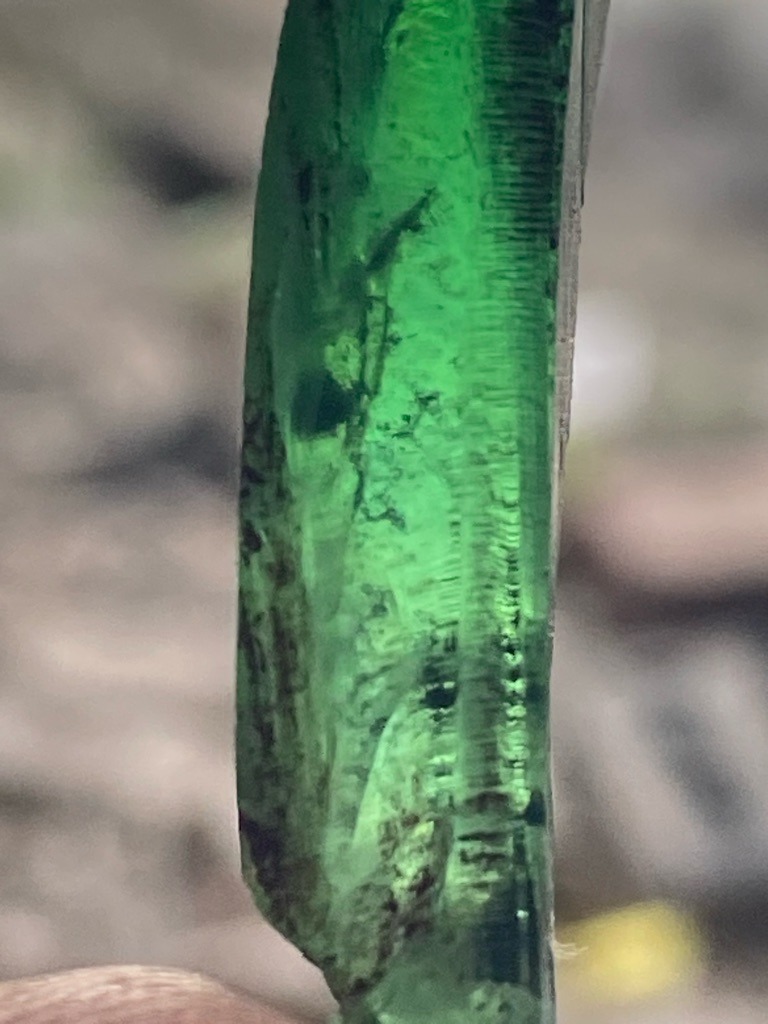Not a diamond; this is a natural green crystal, likely tourmaline or emerald showing typical prismatic habit and vertical striations. - Rough crystal, prismatic columnar form with natural faces