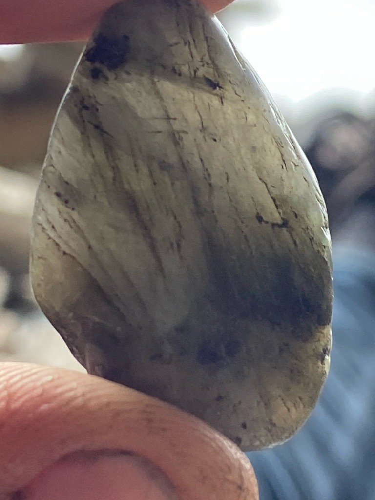 Not a diamond; this is a mineral specimen, likely labradorite or another feldspar given the surface striations and chatoyant/sheen characteristics. - Freeform cabochon or rough tumbled stone