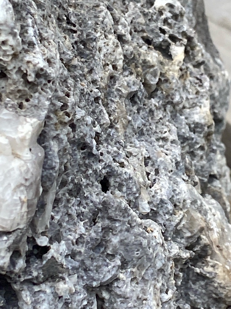 Not a diamond; this image displays rough geological matrix rock or limestone formation, possibly containing quartz or calcite veins, but no cut or polished diamond is present. - Not applicable (raw, uncut matrix rock)