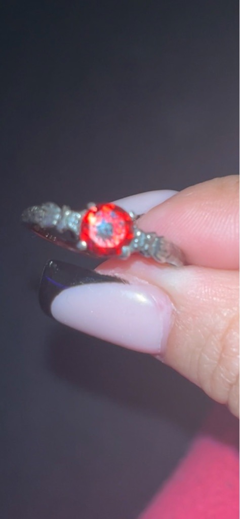 Not a diamond; this gemstone appears to be a colored synthetic stone or colored cubic zirconia, possibly a ruby substitute due to the strong red fluorescence/color. - Round Brilliant