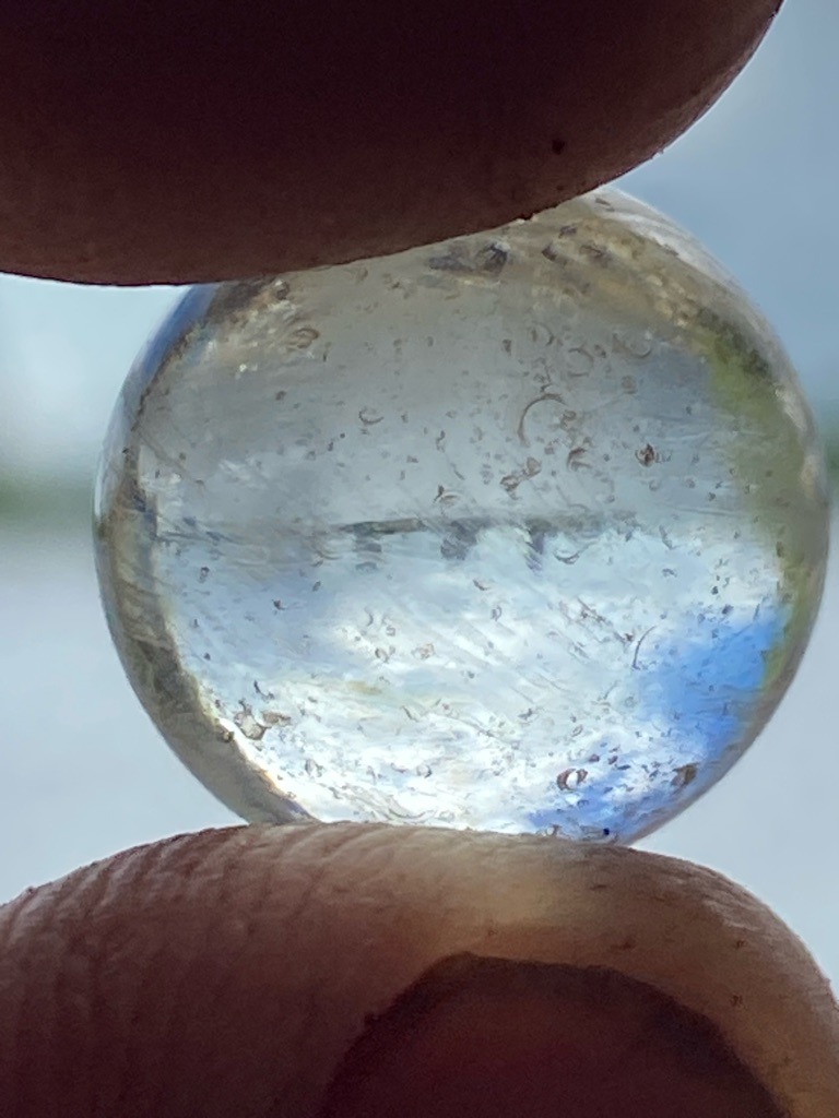 Not a diamond; appears to be a glass marble containing numerous gas bubbles and internal flow lines. - Spherical / Sphere