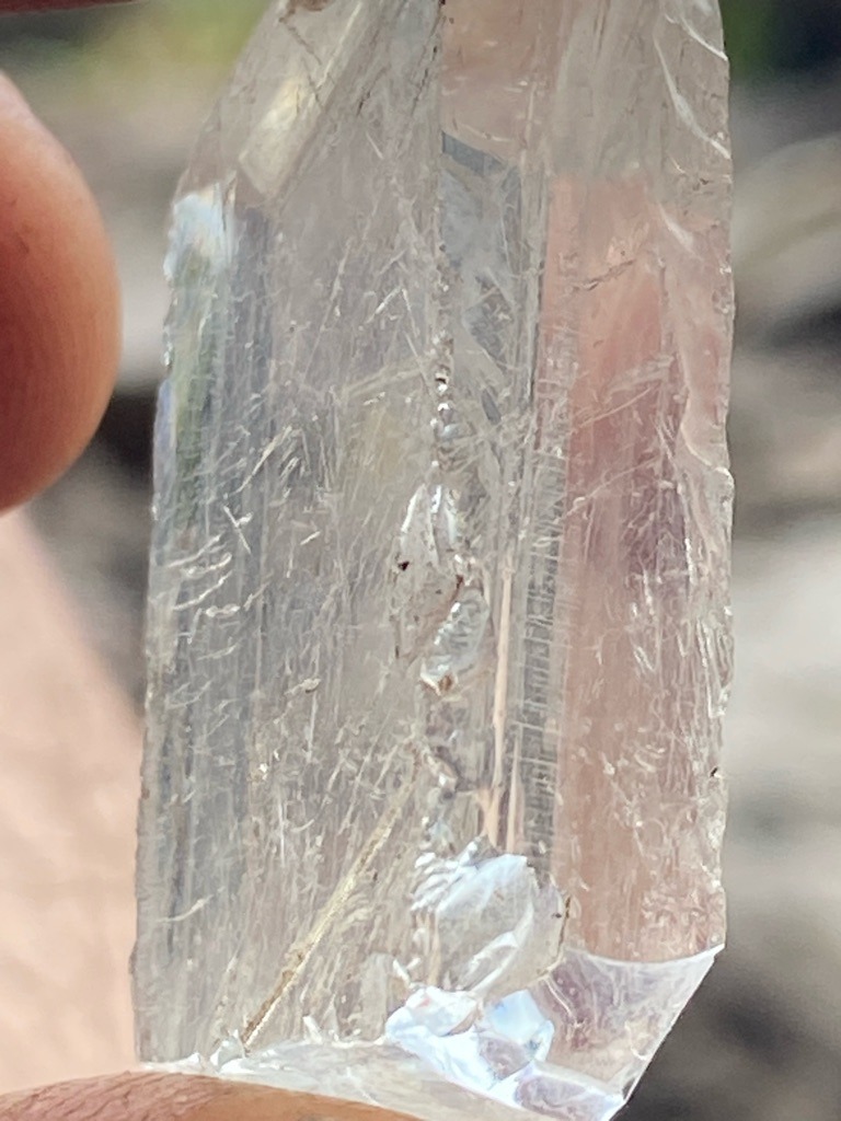 Not a diamond; this specimen appears to be rough quartz crystal or a similar silicate mineral based on the striated prismatic habit. - Uncut rough prismatic crystal with natural crystal faces and striated termination.