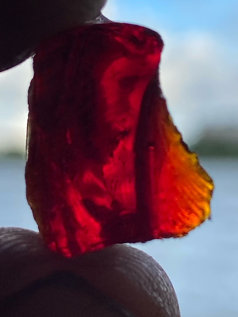 Not a diamond; visual characteristics strongly suggest colored glass, slag, or a low-value colored gemstone rough such as red quartz or corundum, requiring physical testing for definitive identification. - Uncut rough / irregular fragment
