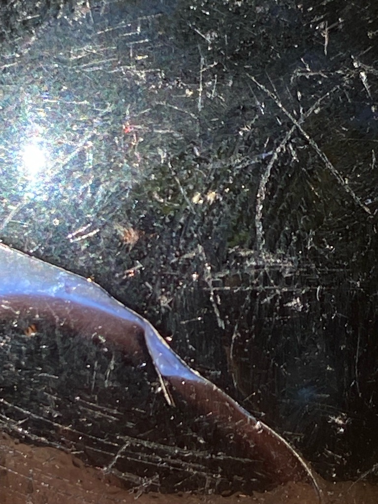 Unable to determine; the image displays a surface texture with scratches and reflections, but no distinct faceted diamond is visible. - Unknown