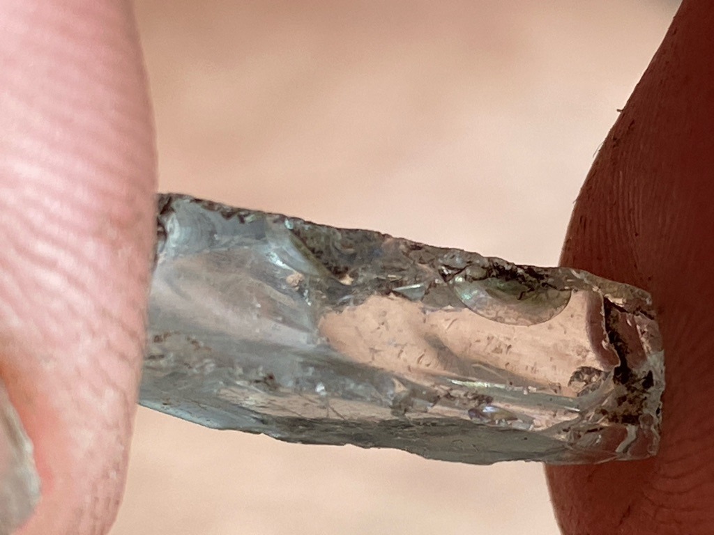 Not a diamond; appears to be industrial glass, slag, or a synthetic silicate material showing conchoidal fracture and surface bubbles. - Rough irregular bar / fragment
