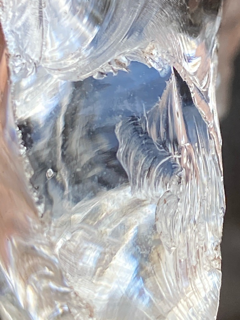 Not a diamond; this appears to be quartz, glass, or another transparent crystalline mineral showing conchoidal fracture patterns rather than diamond crystal faces or cleavage. - Uncut or raw crystalline fragment with conchoidal fracture surfaces