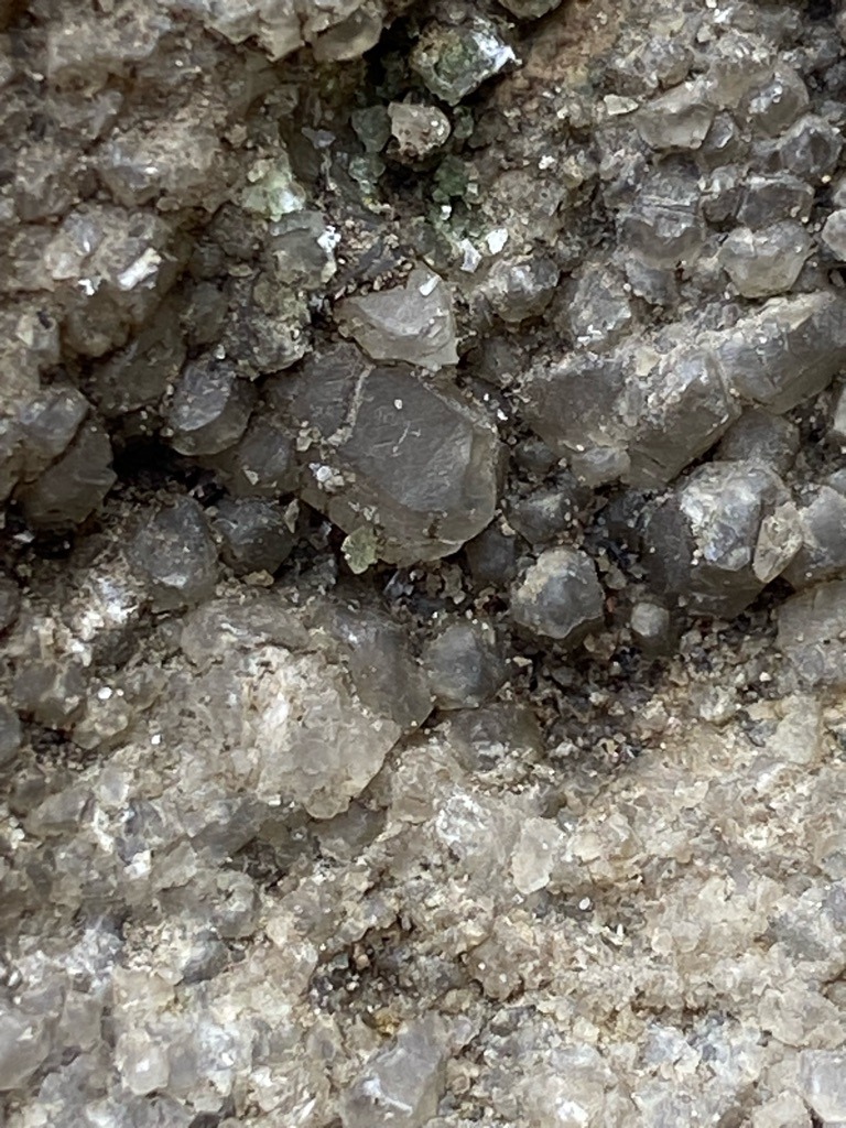 Not applicable; the image displays raw matrix rock containing rough mineral crystals or quartz aggregates, not cut or uncut gem-quality diamonds. - Irregular crystalline and granular aggregates within host rock