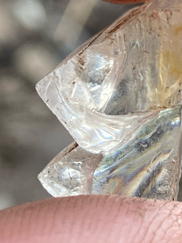 The specimen shown in the image appears to be rough, untreated mineral crystal, likely quartz or a similar crystalline rock rather than a genuine diamond crystal based on the conchoidal fracture patterns and surface features. - Rough crystal shard with irregular, broken form, not possessing a standard diamond cut shape.