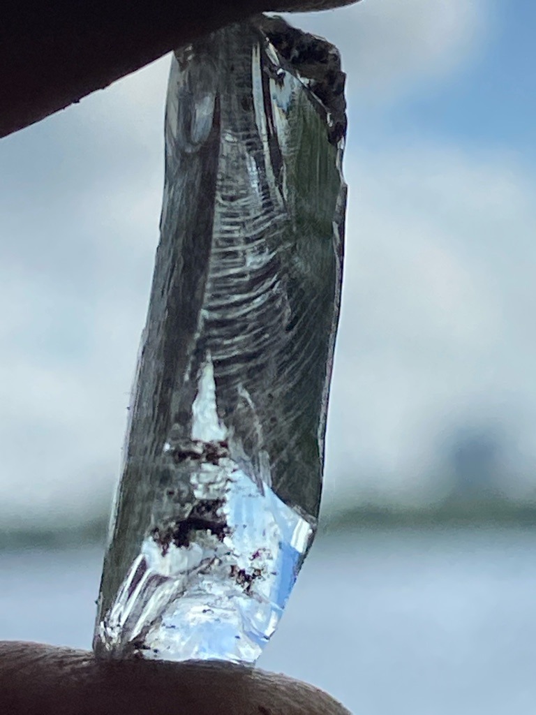 Natural diamond rough crystal, displaying characteristic elongated form and surface striations (growth lines). - Uncut or raw elongated crystal, potentially an octahedral or distorted dodecahedral habit.