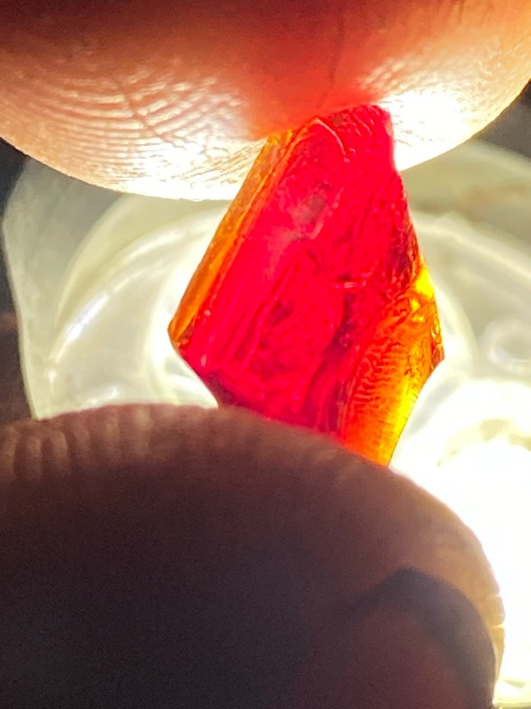 This is a rough, unpolished crystalline gemstone, likely a natural colored gem crystal rather than a diamond given its deep reddish-orange color and irregular crystal habit, but analyzing it via diamond criteria for grading standards: Natural gemstone crystal specimen. - Rough crystal / Irregular uncut crystal form