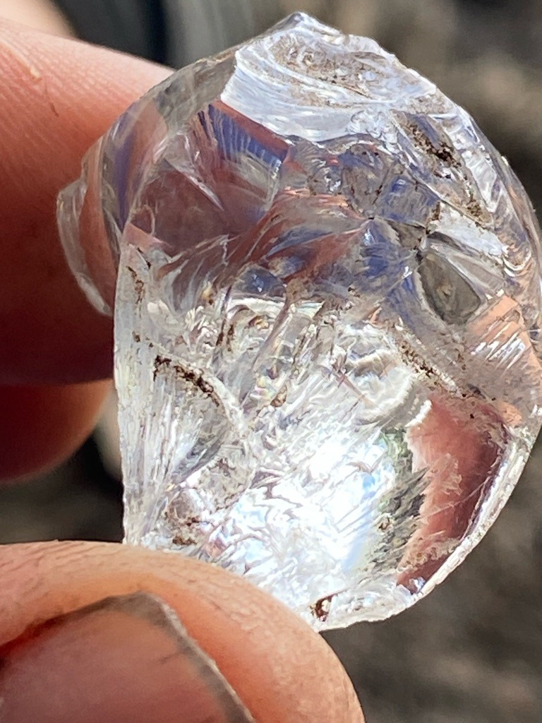 Not a diamond; visual characteristics strongly suggest raw quartz, glass, or a synthetic simulacrum (such as quartz or glass slag), characterized by conchoidal fracture patterns rather than crystalline diamond octahedron/dodecahedron faces. - Rough, uncut, irregular natural crystal or tumbled chunk, non-standard shape.