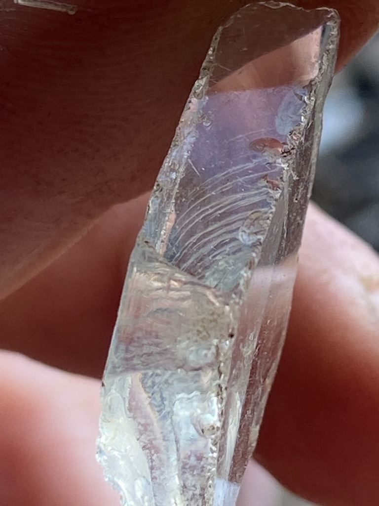 Not a diamond; likely quartz, glass, or a synthetic silicate crystal displaying conchoidal fracture and distinct curved striations. - Raw, unpolished, irregular fragment with natural or broken cleavage/fracture planes.