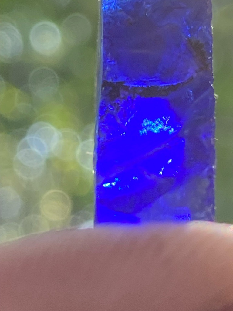 Not a diamond; this specimen appears to be a mineral crystal, potentially fluorite or a similarly reactive fluorescent crystal under UV light, displaying strong blue luminescence. - Rough crystal shard / uncut mineral specimen