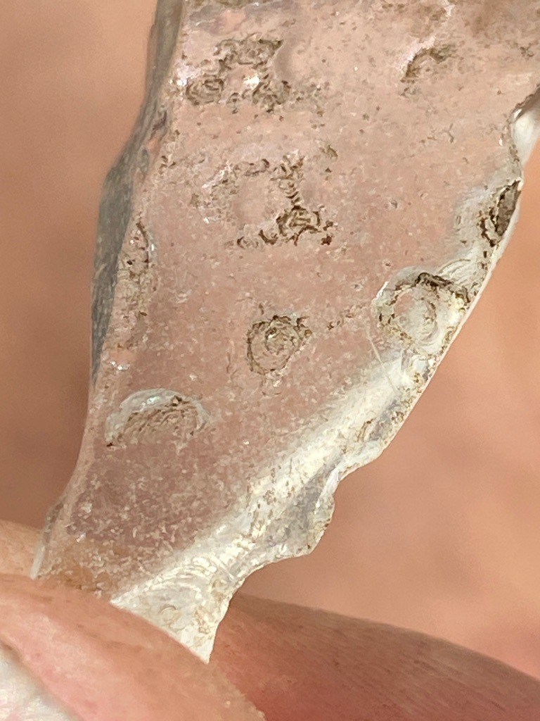 The provided image displays a rough, unprocessed quartz or glassy geological specimen rather than a faceted diamond, showing surface pitting and natural corrosion rather than gem-grade crystallization. - Irregular / Rough Crystal Fragment