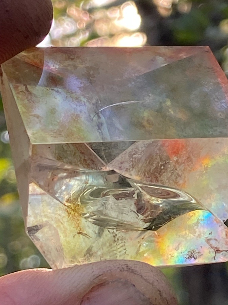 Not a diamond; this is a faceted quartz crystal or potentially glass containing pronounced internal stress fractures, feather inclusions, and distinctive rainbow iridescence from thin-film interference or micro-fractures. - Custom carved or heavily faceted geometric block / modified cube shape.