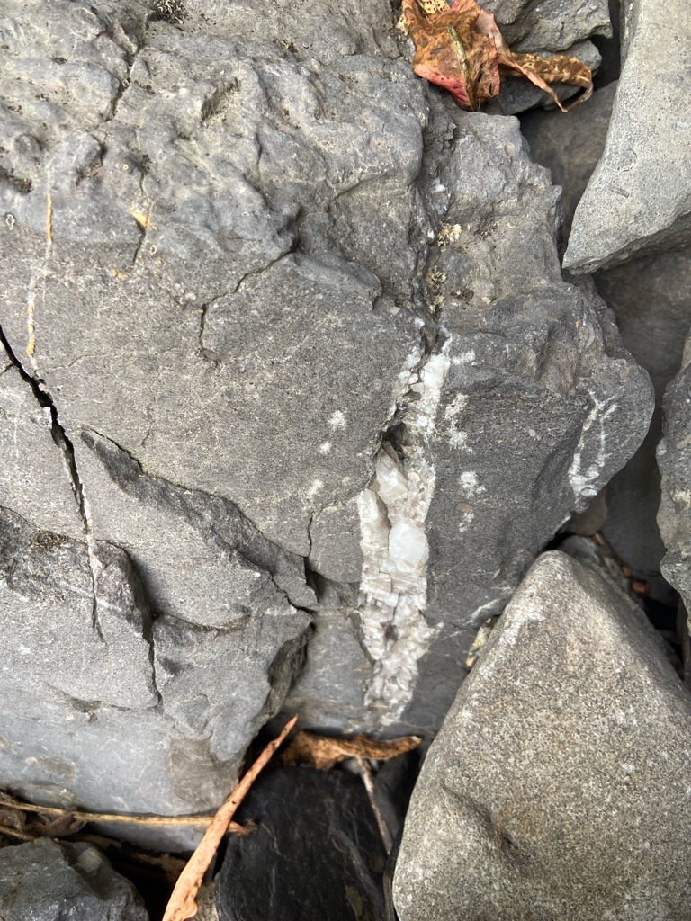 Not a diamond; this image displays a geological vein of quartz or calcite crystallized within a host rock matrix, commonly associated with hydrothermal mineral deposition. - Rough, unpolished, crystalline habit within a rock fracture (not faceted).