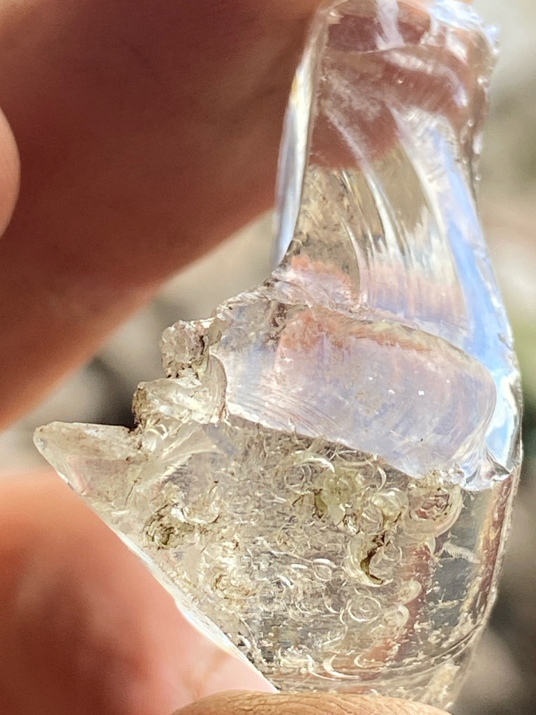 Not a diamond; this is a piece of melted glass or slag, as evidenced by the conchoidal fracture and trapped air bubbles visible in the structure. - Irregular raw or fragment shape (Not faceted)
