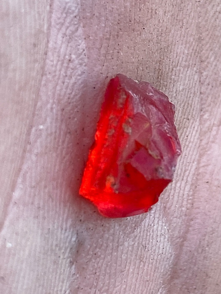 The specimen shown in the image appears to be a rough gemstone, likely a ruby or red spinel, rather than a diamond. Naturally occurring red diamonds are extremely rare, and this sample lacks the characteristic crystal habit and adamantine luster of rough diamond. - Rough uncut crystal / irregular fragment with natural crystal faces.
